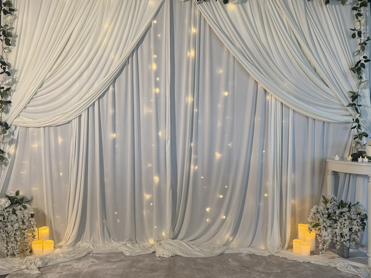 The Styled Backdrop: ivory drapes with silk florals, twinkle lights, and candlelight